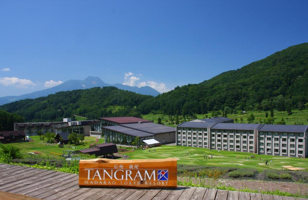 a hotel with a sign in front of a mountain range at Hotel Tangram in Shinano