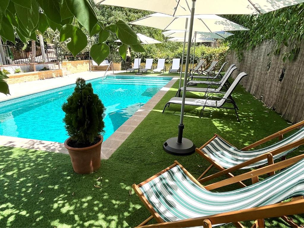 una piscina con sillas y sombrillas junto a una piscina en XXVI- Finca La Cantara - La Cantara Azul, en Ronda