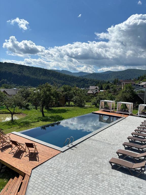 a pool with chairs and a view of the mountains at Guculka Apartments in Yaremche