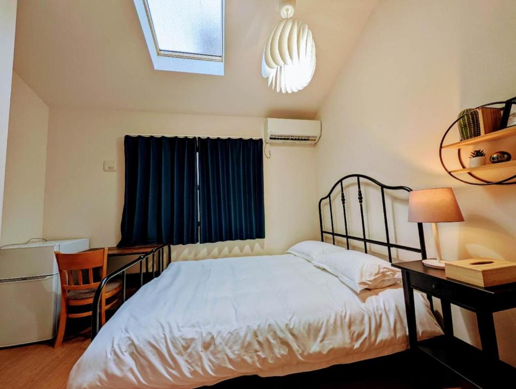 Un dormitorio con una cama y un escritorio y una ventana. en 池袋本町303, en Tokio