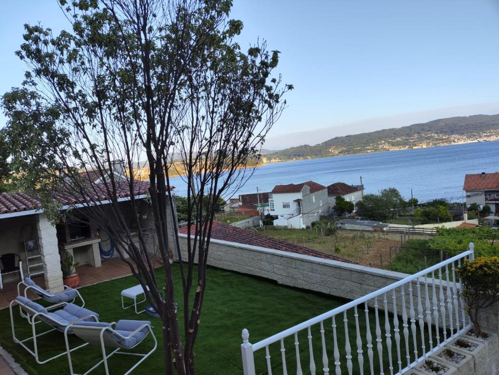 a balcony with two chairs and a tree and the water at Casa PEPE in Combarro
