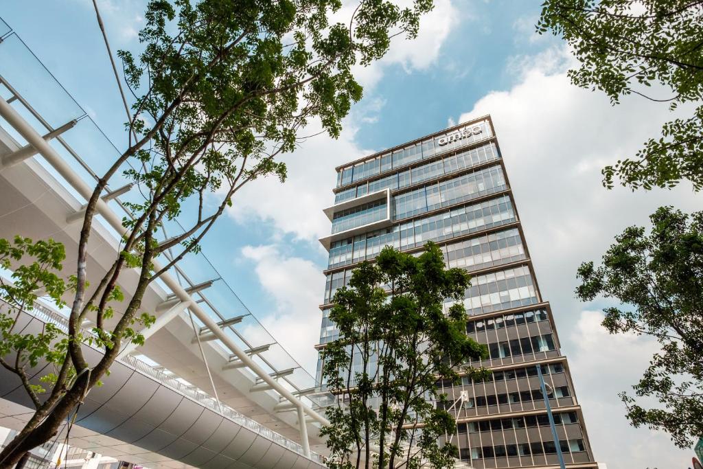 a tall building with trees in the foreground at amba Taipei Songshan in Taipei