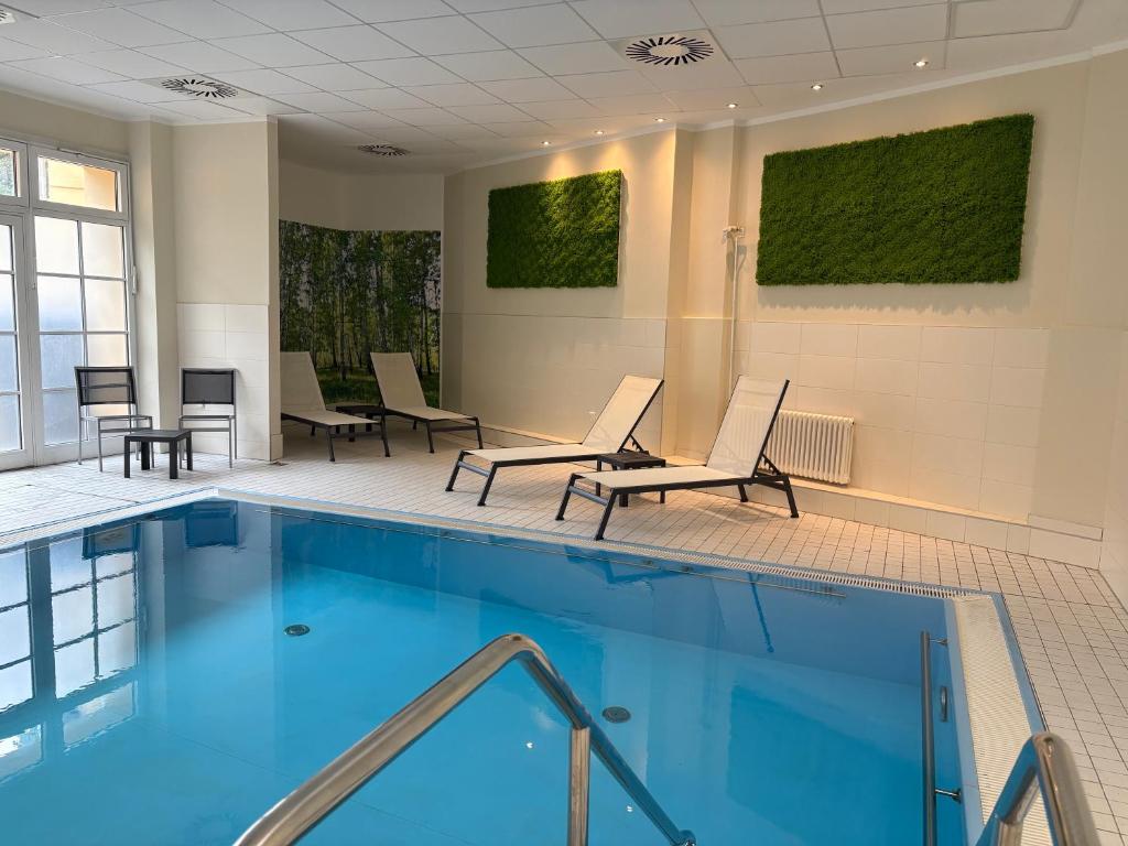ein Schwimmbad mit Liegestühlen und Tischen in einem Gebäude in der Unterkunft Hotel und Restaurant Kranichsberg in Woltersdorf