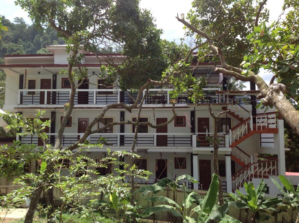 a large white building with balconies and trees at St. John Island View Pensionne in El Nido
