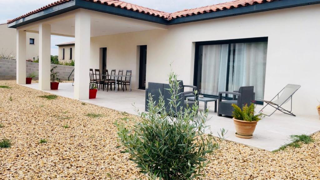 a house with a patio with chairs and a grill at Superbe villa climatisée in Connaux