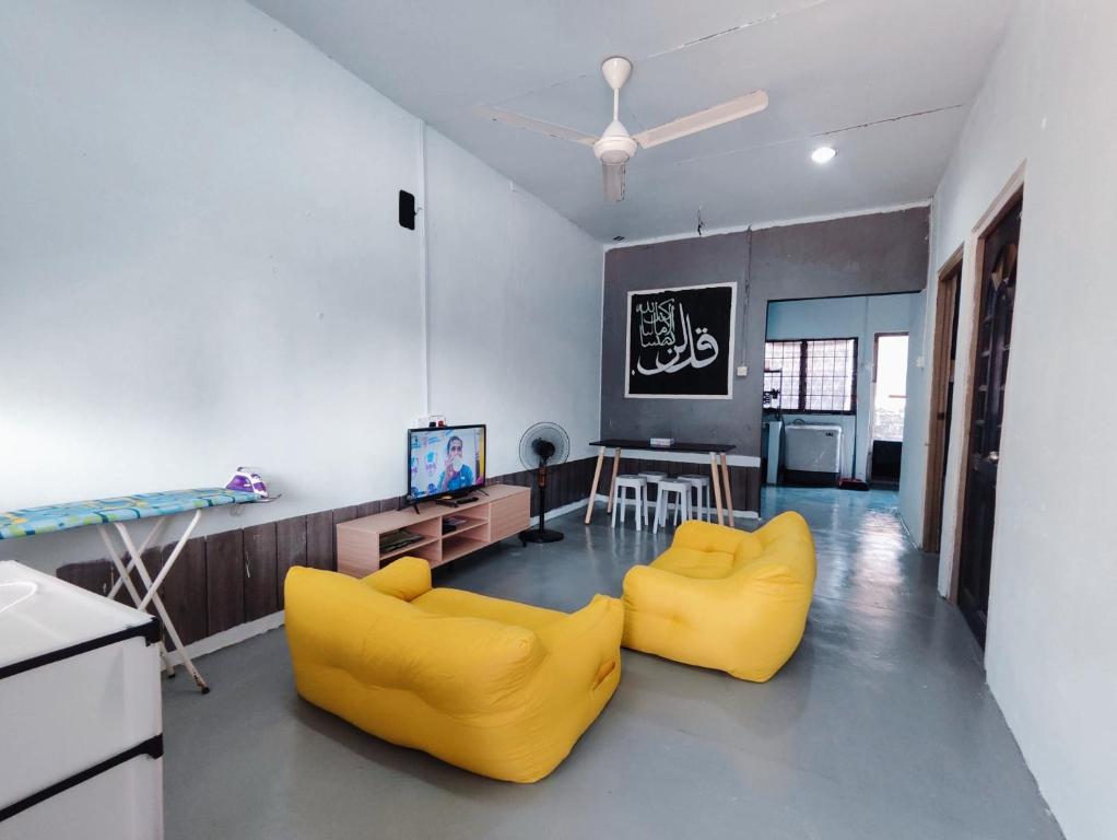 a living room with two yellow chairs and a television at BUDGET Homestay RumahTamu TELIPOT Kota Bharu in Kota Bharu