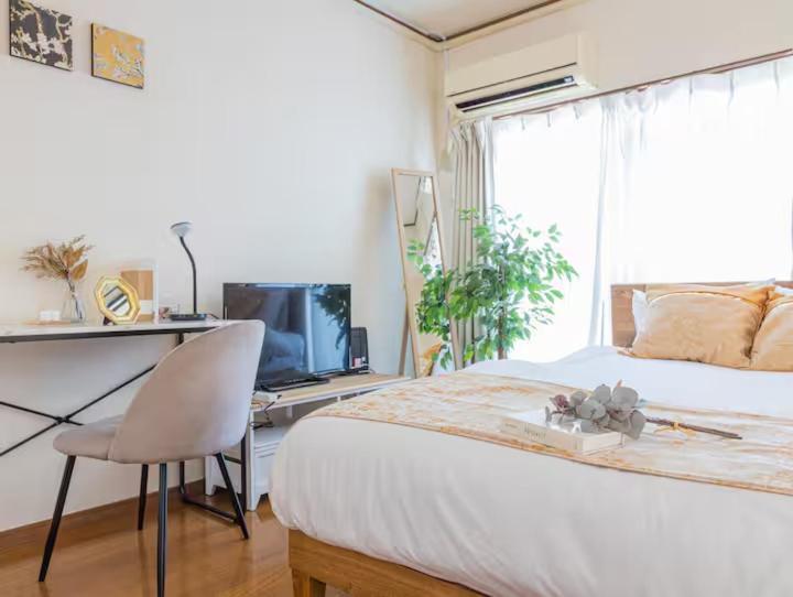 una camera da letto con un letto, una scrivania e una televisione di Tokyo Akari House 駅3分 2BR 40平米快適空間 長期利用に人気 飲食店多数便利 羽田 a Tokyo