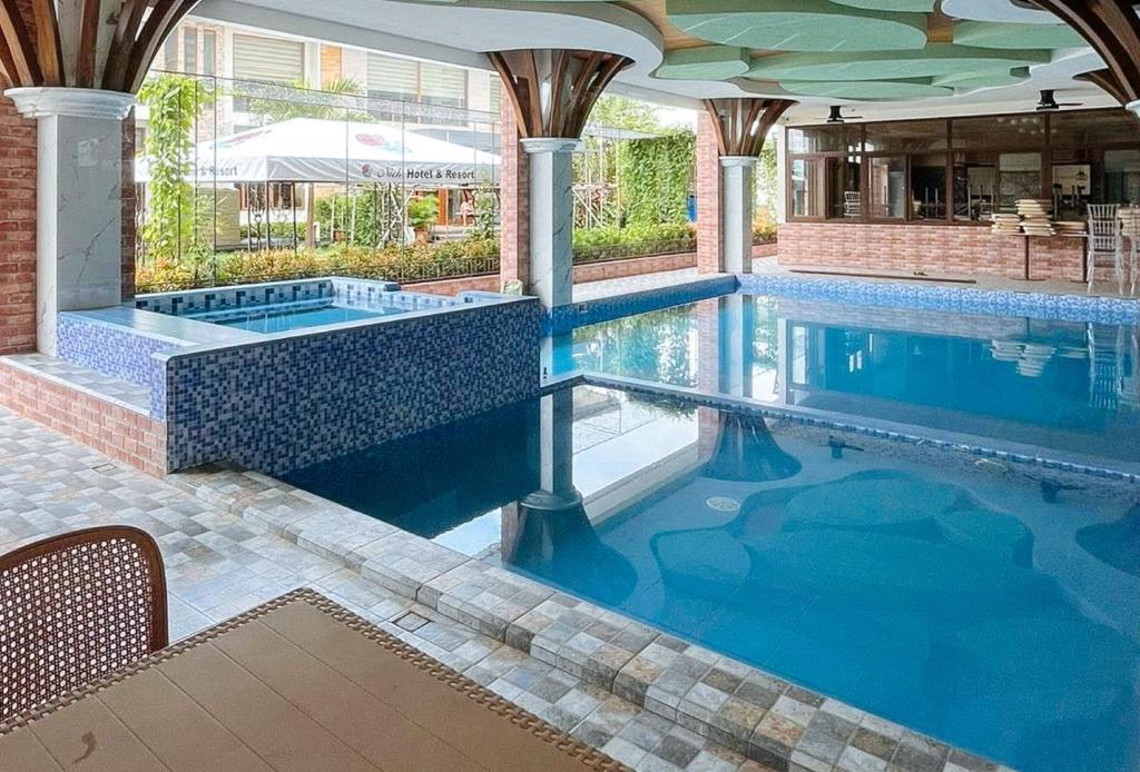 a swimming pool with blue water in a building at RedDoorz Plus at Nick Hotel Guimba in Guimba