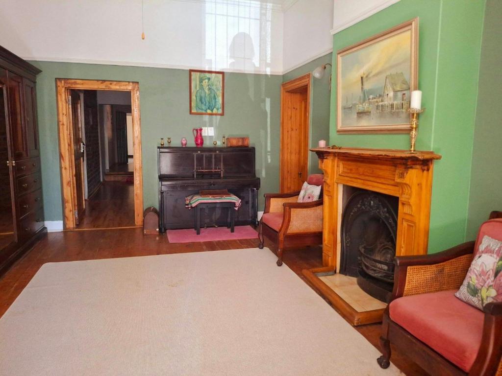 a living room with a fireplace and green walls at Ruitersrust in Fauresmith