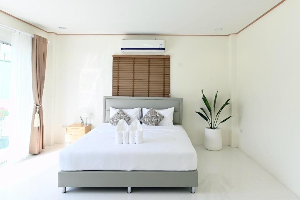 a white bedroom with a large bed with white sheets at White house poolvilla บ้านพักพูลวิลล่า ชุมพร Pp2 in Chumphon