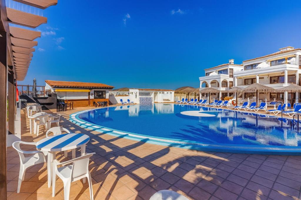 a swimming pool with chairs and umbrellas at a resort at Pebble Beach in San Miguel de Abona