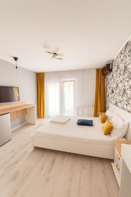 a white bedroom with a large bed and a tv at Casa Maxim Eforie Nord in Eforie Nord