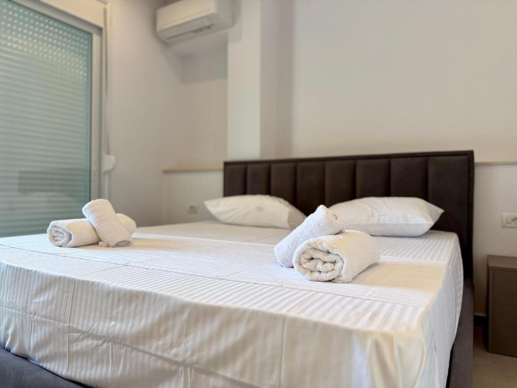 a bedroom with two beds with white sheets and towels at Vlora forest Apartments in Vlorë