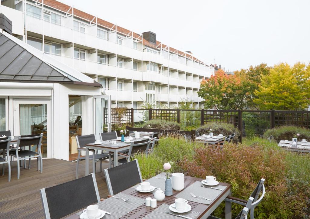 a patio with tables and chairs and a building at Living Hotel Nürnberg in Nuremberg
