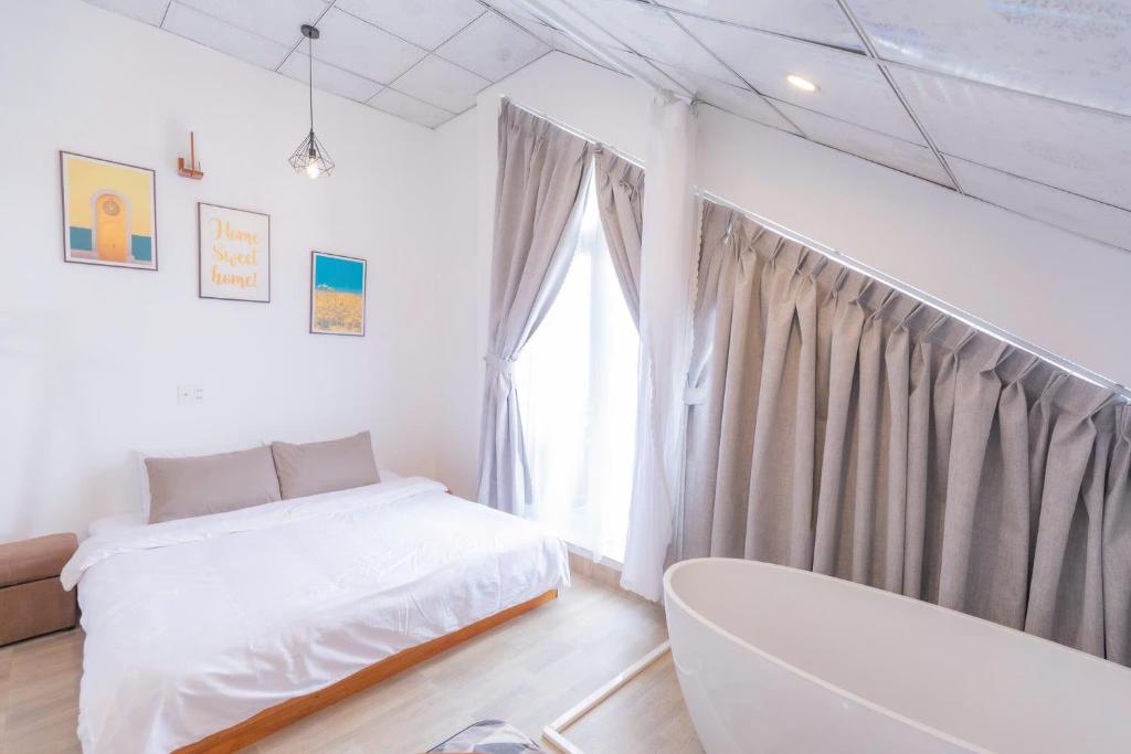 a white bedroom with a bed and a tub at Blue Windy Đà Lạt Homestay in Da Lat