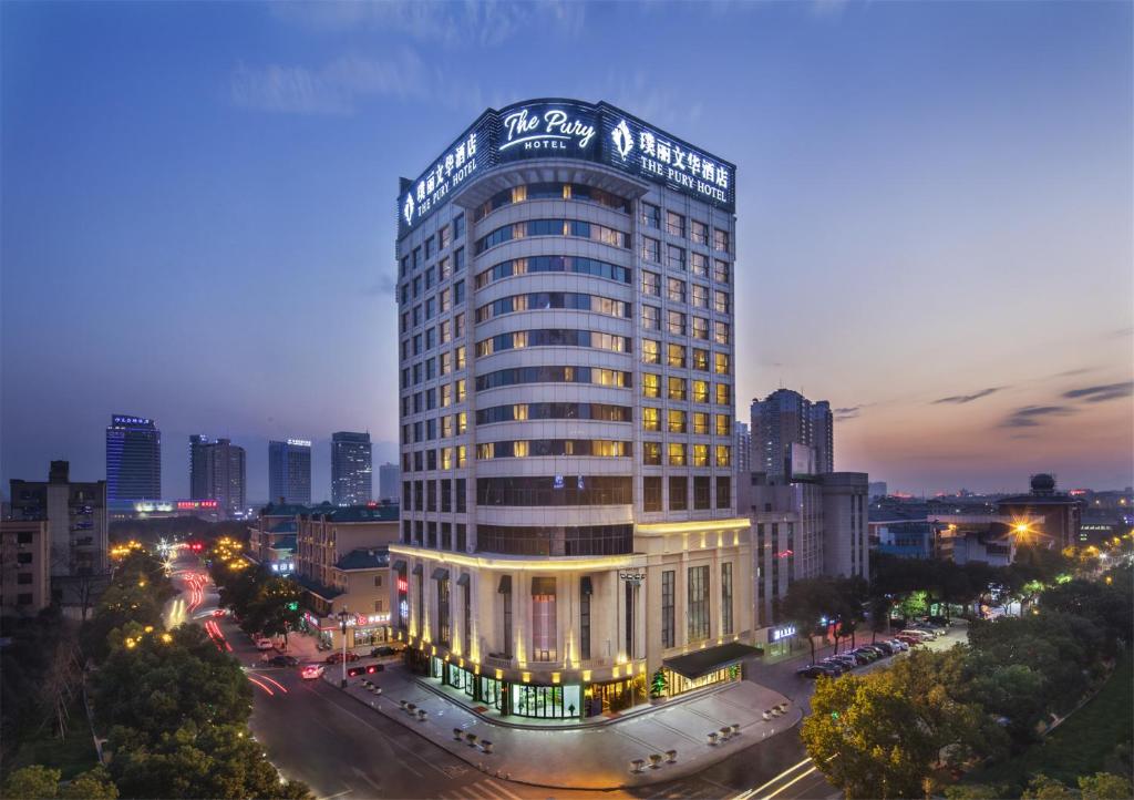 un edificio alto con un cartel encima en The Pury Hotel, en Yiwu