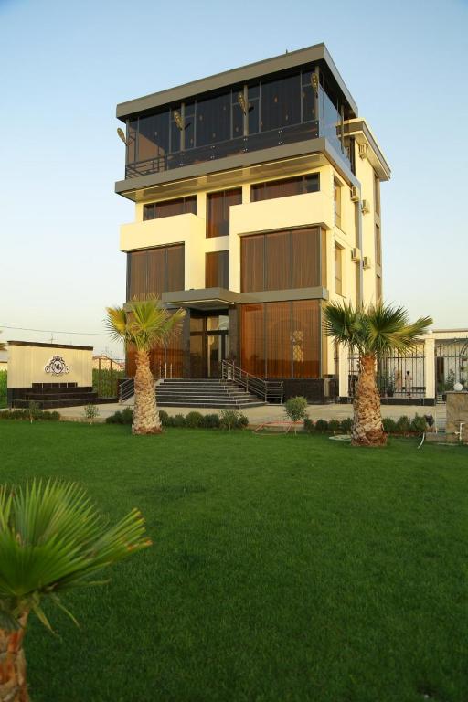 a large building with palm trees in front of it at Milano Garden Plaza Samarkand in Samarkand