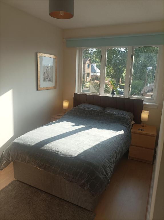 a bedroom with a bed and two windows at Double room, Belhaven, Dunbar in Dunbar