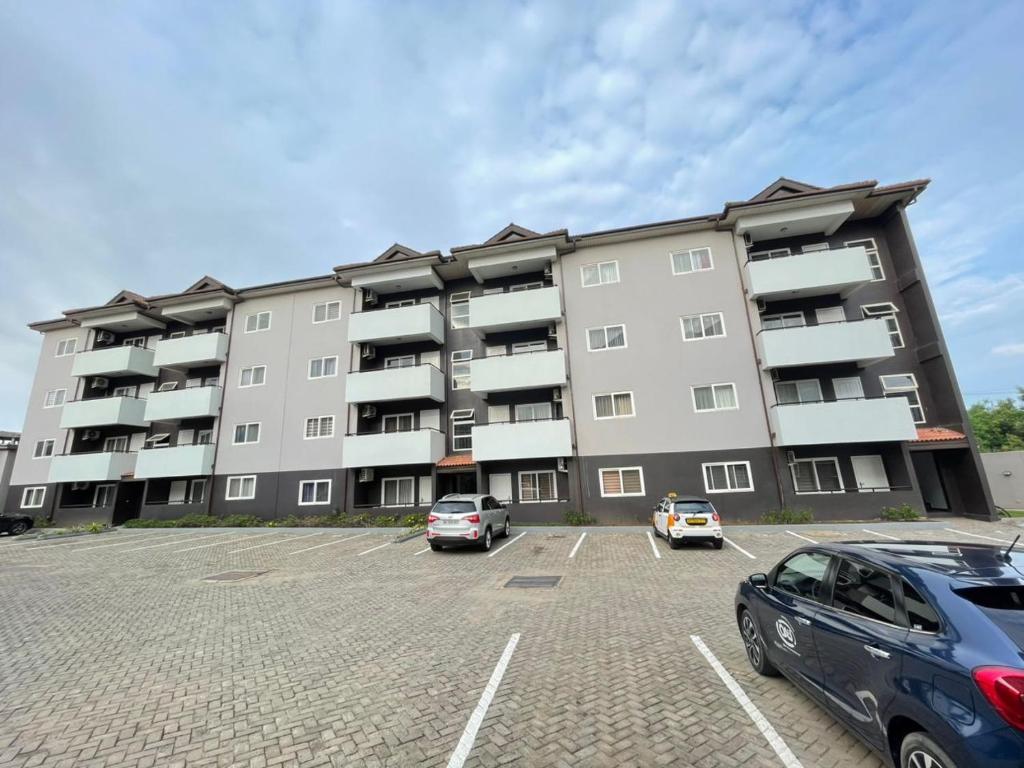 een groot appartementengebouw met auto's geparkeerd op een parkeerplaats bij Sunny's Place Luxury Apartments in Accra