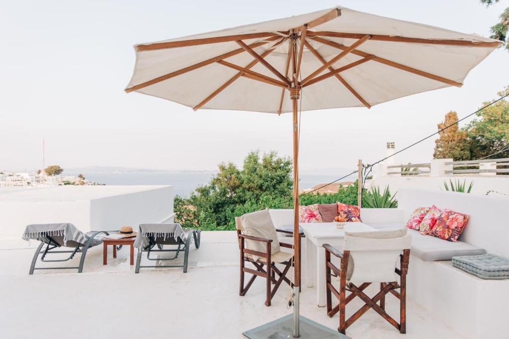 an umbrella on a patio with a table and chairs at Yiayias Home Sifnos in Apollonia