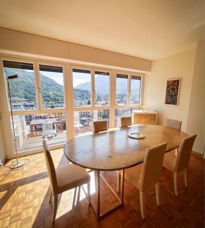 a dining room with a table and chairs and windows at Art & Lake Apartment in Lecco