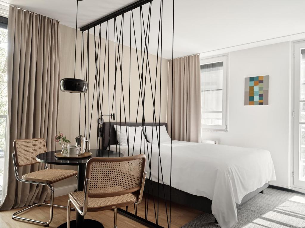 a bedroom with a bed and a table and chairs at Bob W Munich Schwabing in Munich