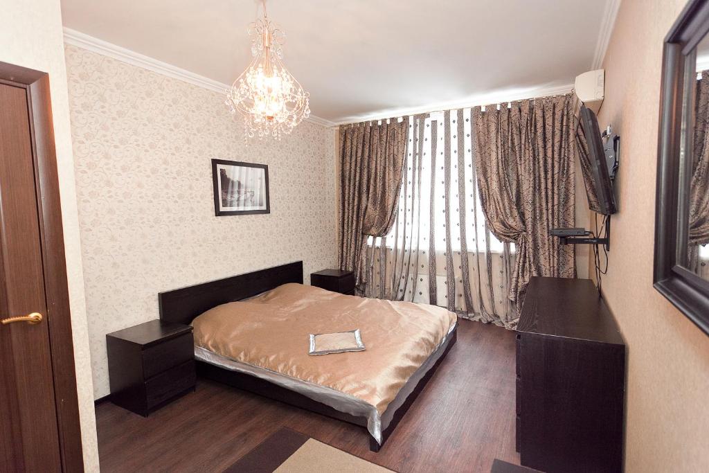 カザンにあるApartment Grand Kazan on Chistopolskaya 76のベッドとシャンデリア付きの小さなベッドルーム1室