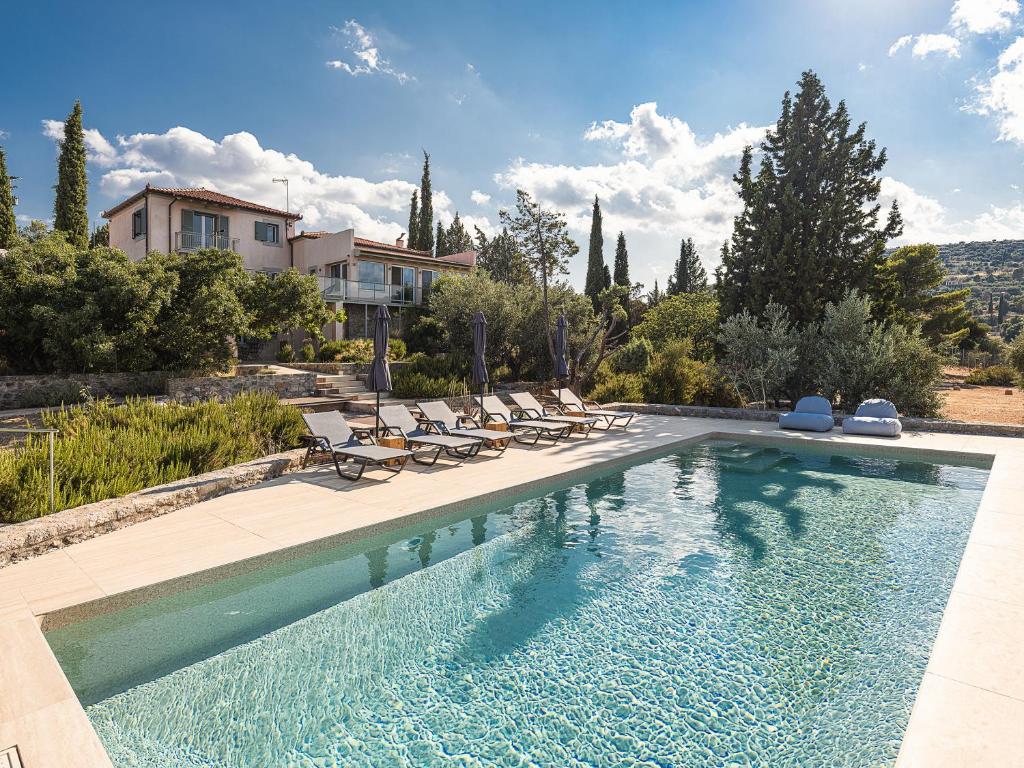 a swimming pool with chairs and a house at Rosmarino Villa Galaxidi in Galaxidhion