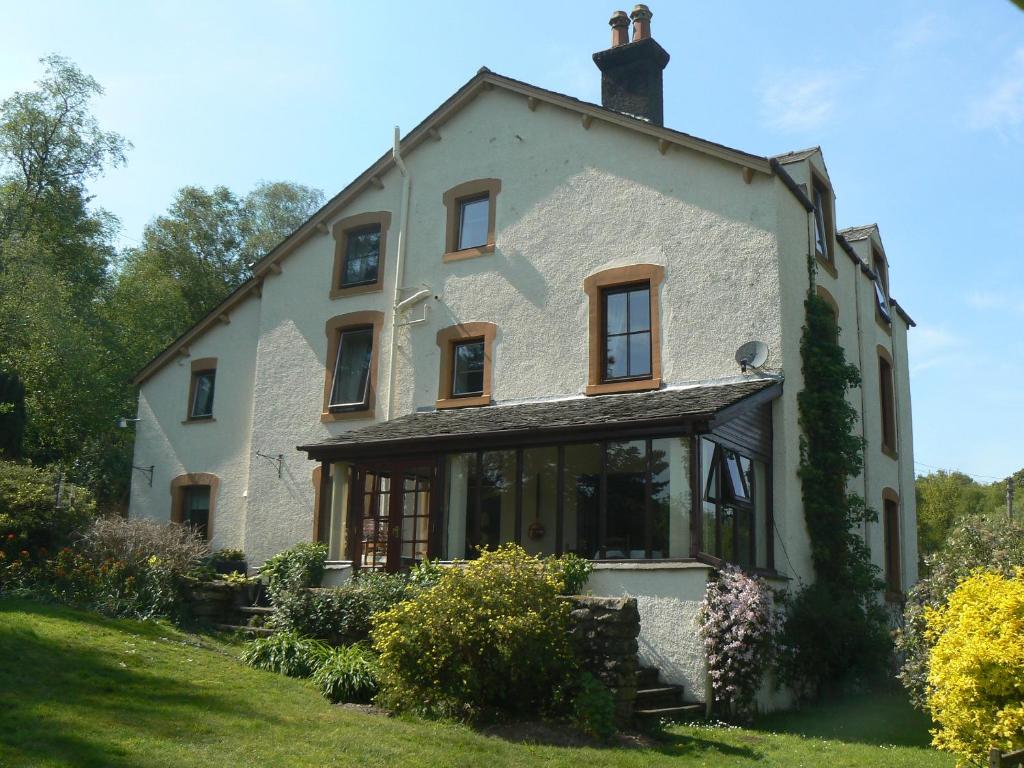 a large white house on a grassy field at Forest How Guest House in Eskdale