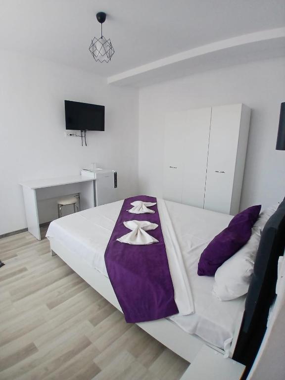 a bedroom with a bed with a purple blanket on it at Vila Atlas Constanta in Constanţa