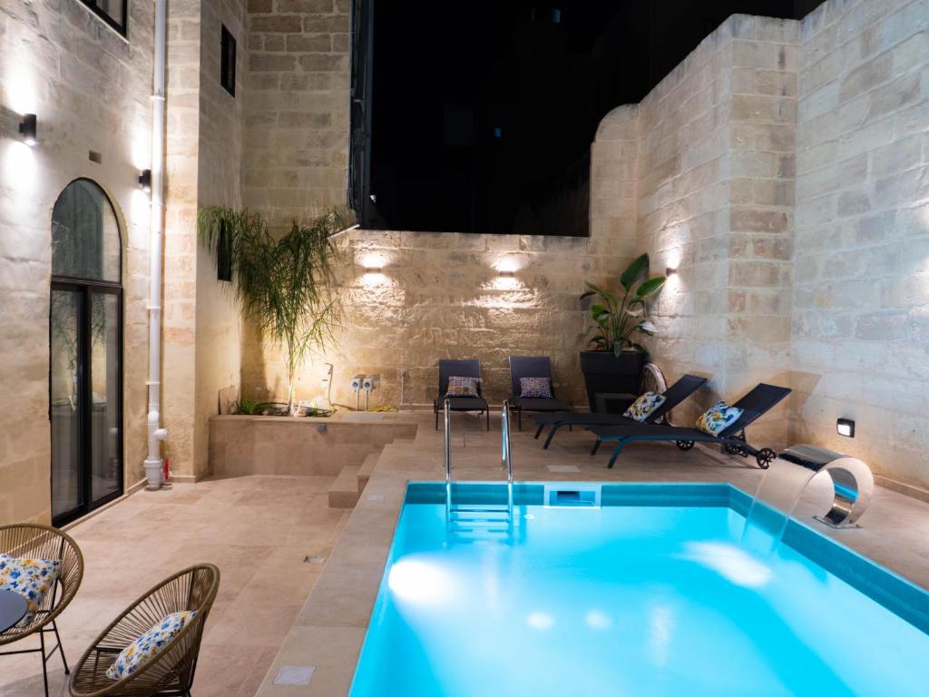a pool in a room with chairs and a couch at Villa Luma With Heated Pool, Jacuzzi, Gym, Sauna and Cinema Room in Sliema