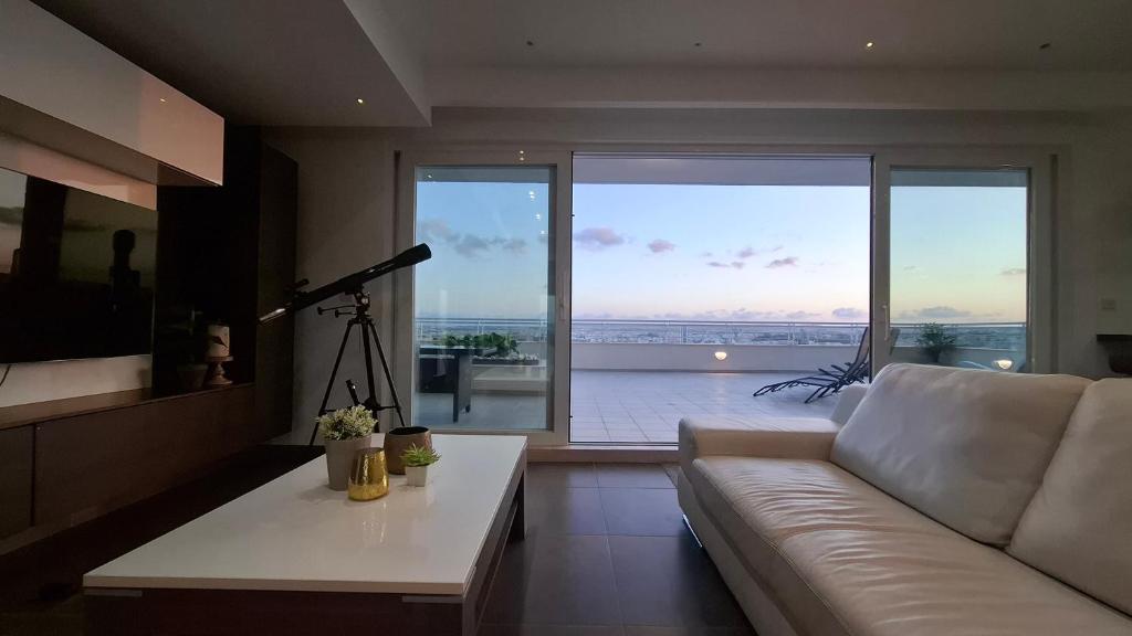 een woonkamer met een witte bank en een groot raam bij Veduta Panoramika in Sliema