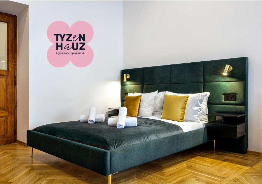 a bedroom with a large bed with a green headboard at Golden Market Square Apartments by Tyzenhauz in Kraków