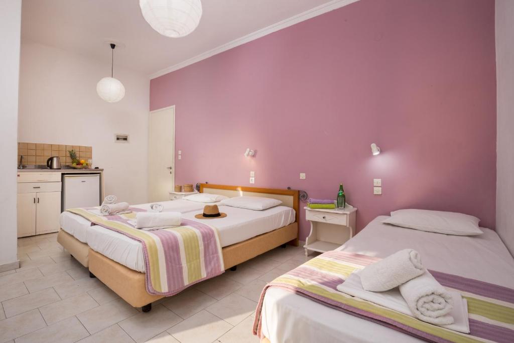 two beds in a bedroom with a purple wall at Island Kavos Annex studios in Kavos
