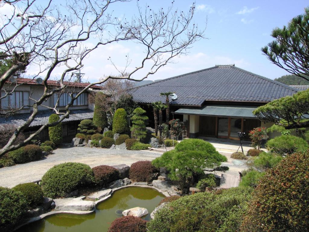 einen Garten mit einem Teich vor einem Haus in der Unterkunft Momoyama in Matsumoto