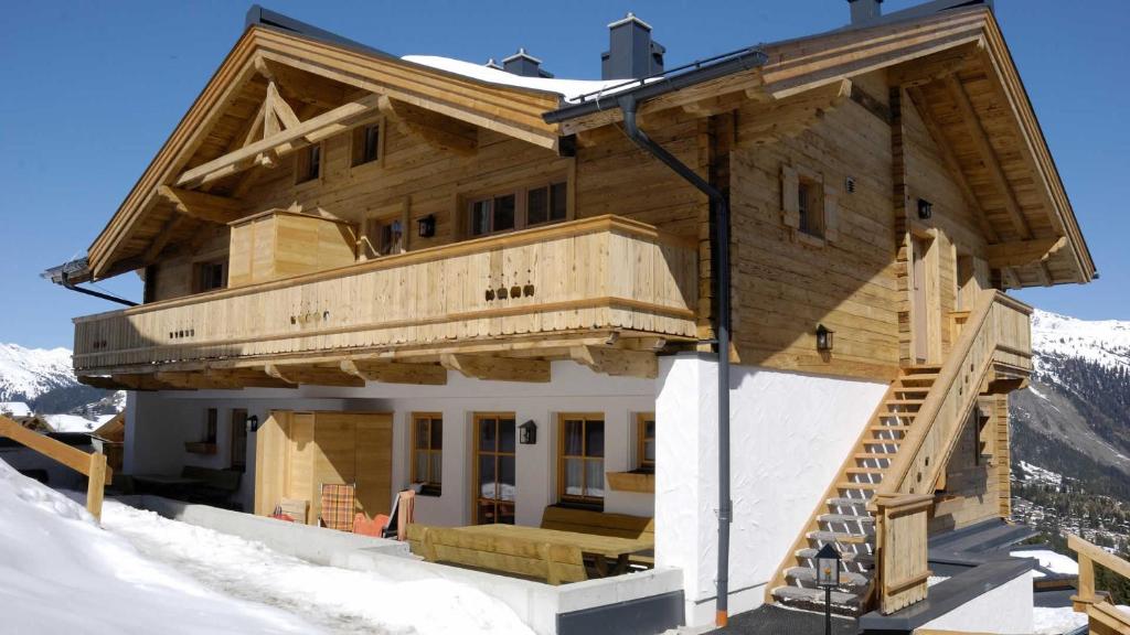 a large wooden house with a balcony in the snow at Skihütte Silberleiten, 8 Personen in Krimml
