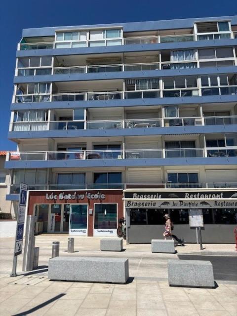une femme assise devant un grand bâtiment dans l'établissement Appartement PLAGE - LES PIEDS DANS L'EAU, à Canet