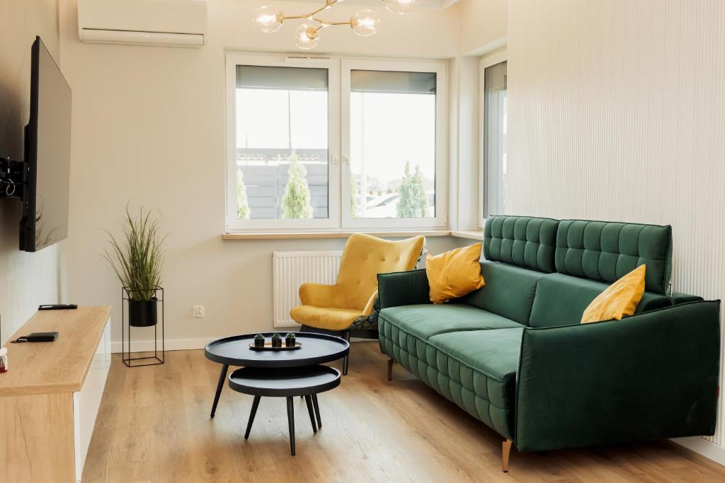 un salon avec un canapé vert et une table dans l'établissement Apartament Komfort, à Uniejów