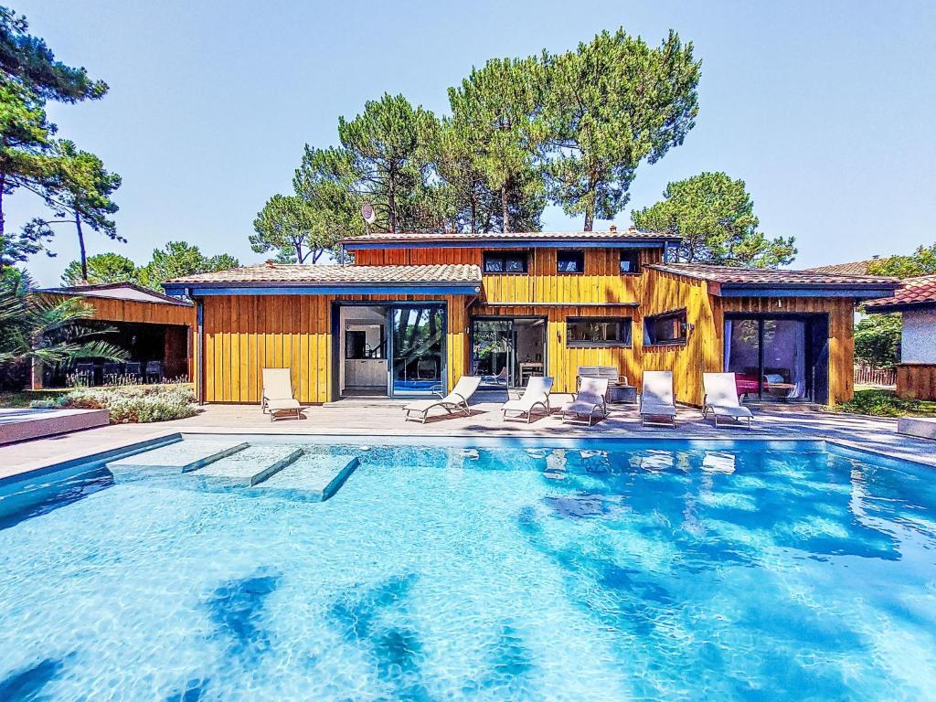 ein Haus mit einem Pool mit Stühlen und einem Haus in der Unterkunft Villa Villa les Verdiers by Interhome in Biscarrosse