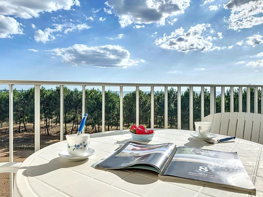 a table with a book and two cups on a balcony at Studio Mer & Soleil-3 by Interhome in Saint-Brévin-lʼOcéan
