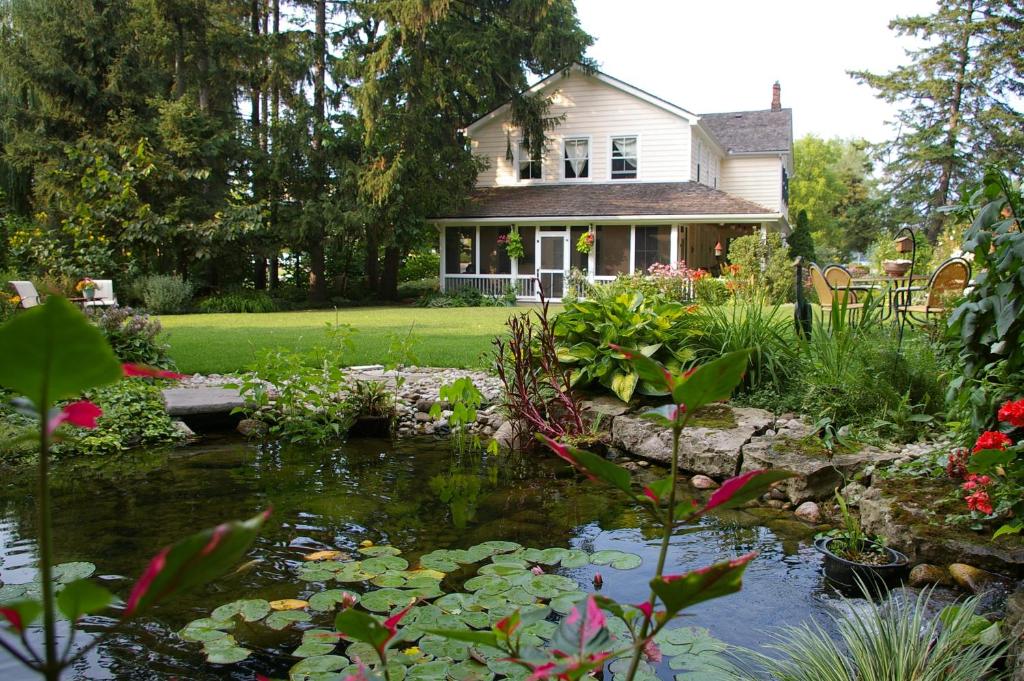 a house with a pond in front of a yard at Royal Manor Bed & Breakfast in Niagara-on-the-Lake