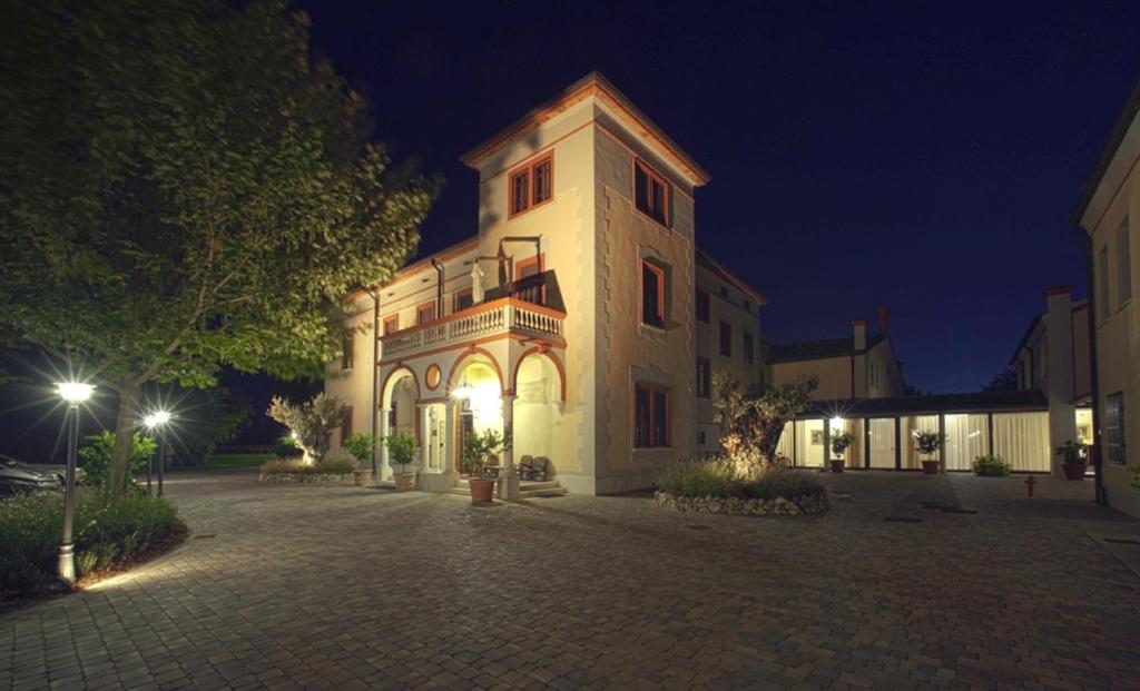 Un grand bâtiment blanc avec des lumières allumées la nuit dans l'établissement Villa dei Tigli 920 Liberty Resort, à Rodigo
