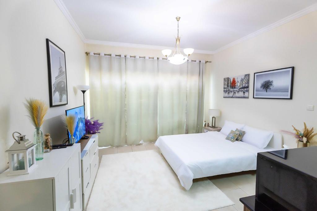 Un dormitorio blanco con una cama y un televisor. en Burj Al Nujoom Downtown Dubai Mall & Burj Khalifa, en Dubái