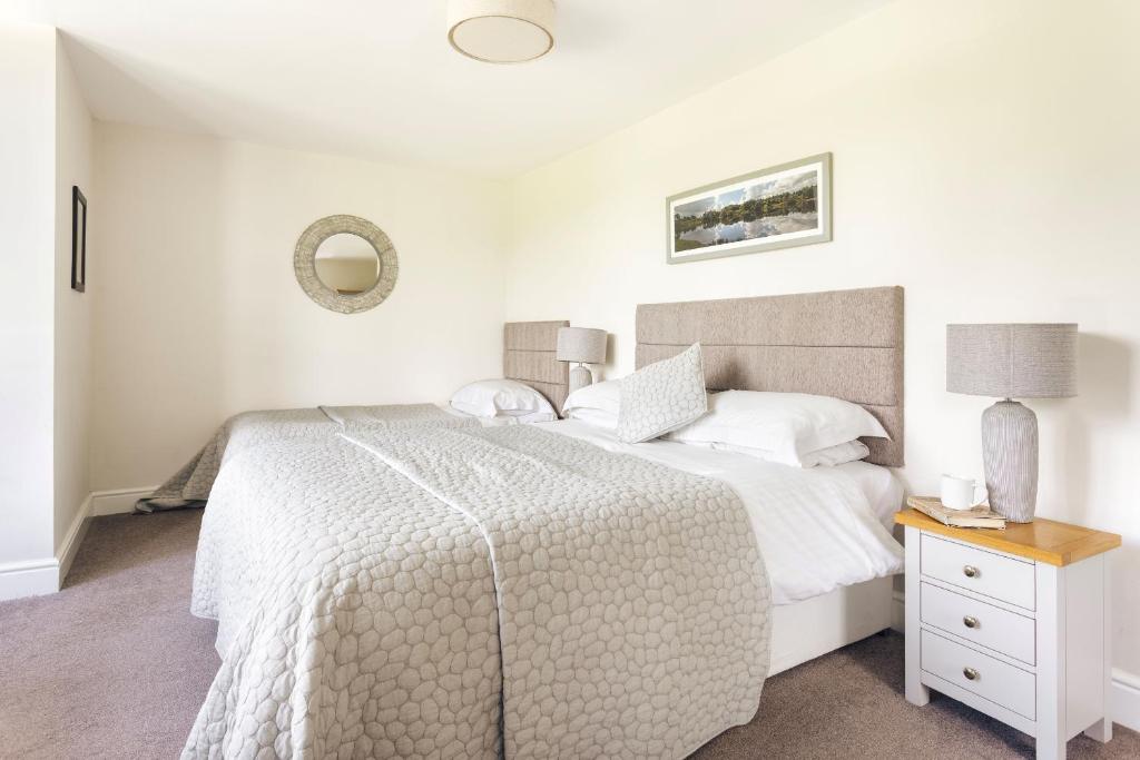 Un dormitorio blanco con una cama y un espejo. en Finest Retreats - Kelsick Villa Guest House - Loughrigg, en Ambleside
