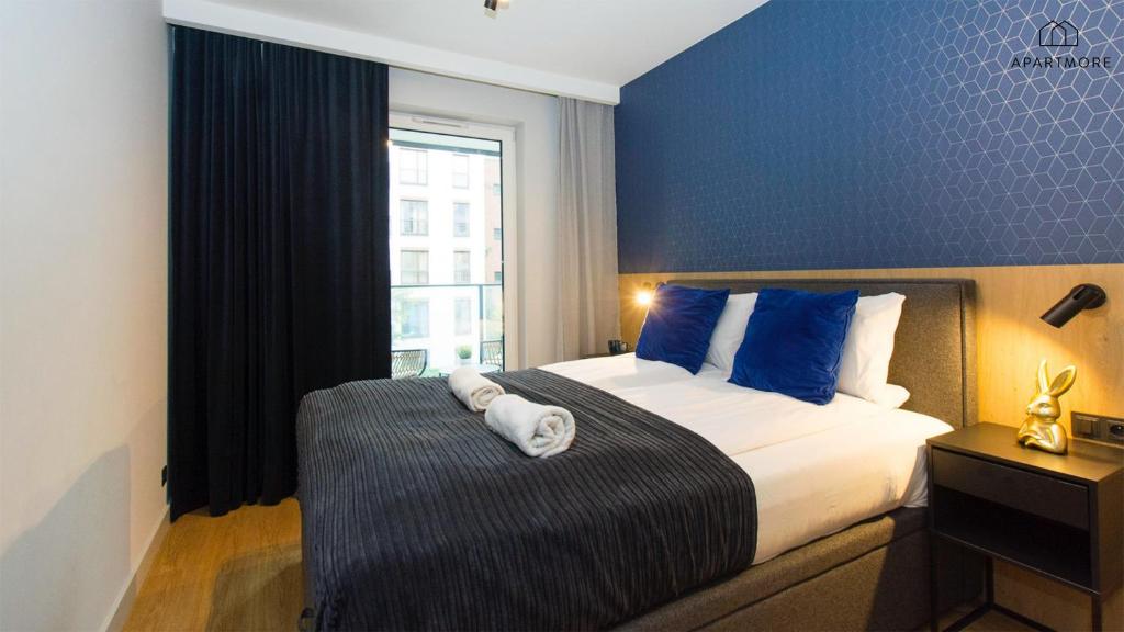 Cozy bedroom with blue geometric wallpaper, double bed, blue accent pillows and folded towels