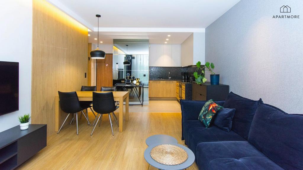 Open-plan living area with navy sofa, wooden dining table for four and modern kitchenette