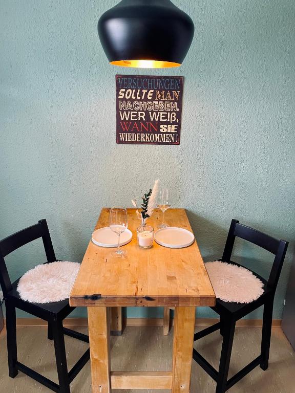 a wooden table with two chairs with wine glasses at Ferienwohnung "Casa Schulzini" im Marburger Südviertel in Marburg an der Lahn