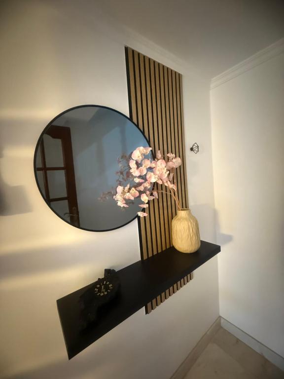 a mirror on a wall with a vase with flowers at Casa Parlera in Ribeira