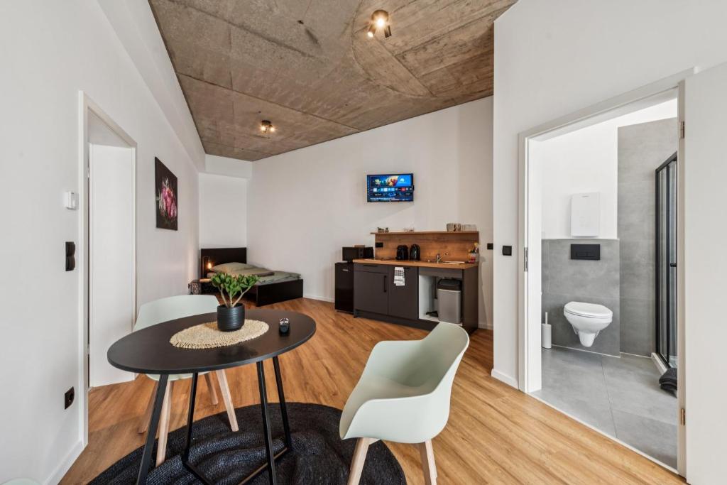 a living room with a table and chairs and a kitchen at Nordbrise by BohnApartments-Modernes Apartment-Zentrum Diepholz-Parken kostenfei in Diepholz