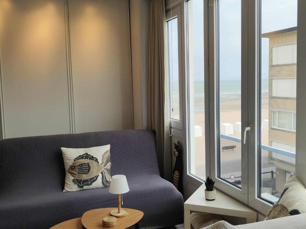 a living room with a blue couch and a window at Sand Rose Studio in Koksijde